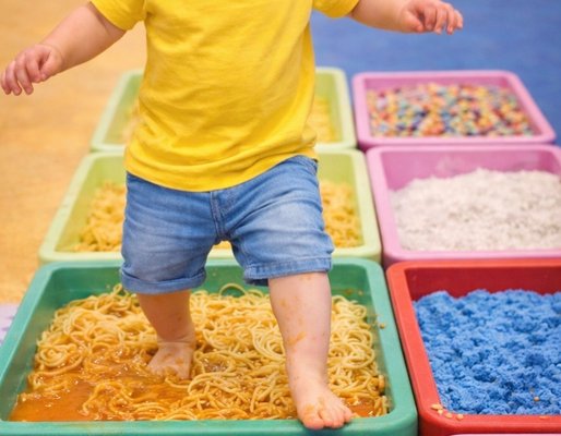 Two girls laughing while playing with building blocks on a foam mat